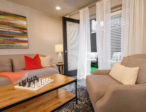 Spacious open living room with a comfy sofa and plenty of seating for guests, plus a private patio just off to the side, seamlessly extending the entertainment outdoors.