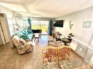 Living room with sliding patio door for easy access to beach, pool, & outdoor activities.