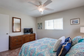 Spacious bedroom with queen size bed, ceiling fan, dresser and closet storage