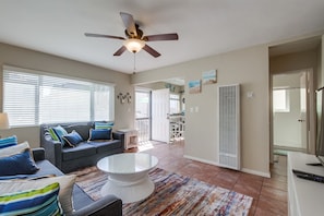 Living room and kitchen with comfy couches, bar table seating, ceiling fan and TV with Roku