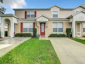 Charming townhouse with a welcoming facade and lush green lawn.