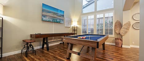 Game room features high ceilings, a pool table, shuffleboard, and giant Smart TV.