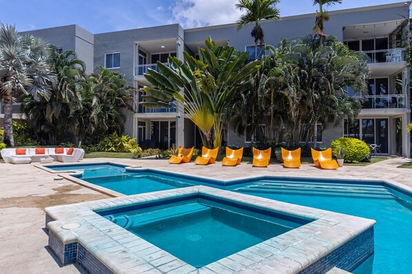 Luxe Shared Pool Area in Oranjestad Aruba - Hot Tub - Relax by the shimmering poolside oasis - Palm trees and tropical plants enhance the vacation feel - Comfy seating Arrangements