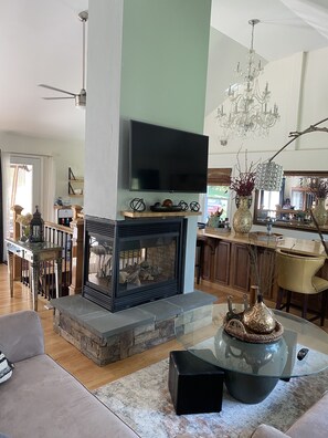 Open great room with fireplace, long kitchen island for gathering and dining