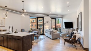 Open concept living area, kitchen, and dining area with wrap aroun balcony and mountain views.