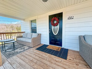 Front porch that is equipped with a sofa and nesting tables