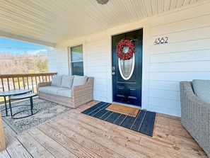 Front porch that is equipped with a sofa and nesting tables