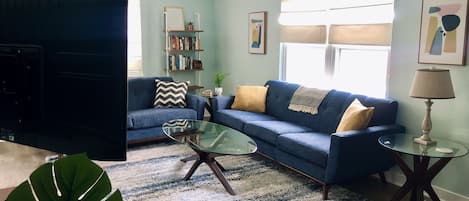 Living Room with comfy seating for 5-6 people, and a 50-in UHD Roku Smart TV.