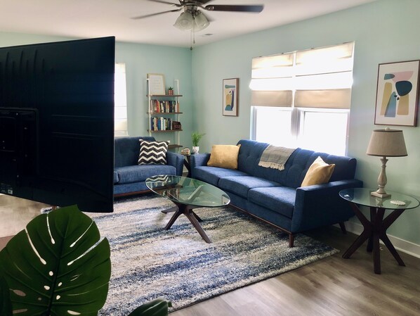 Living Room with comfy seating for 5-6 people, and a 50-in UHD Roku Smart TV.