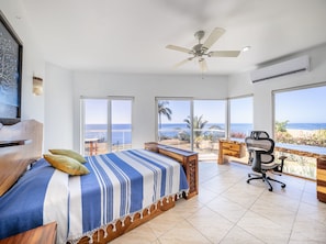 Primary bedroom has a queen size bed, desk, ceiling fan and air conditioning, expansive ocean views