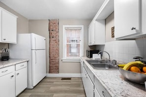 Your full-sized kitchen with a full refrigerator, microwave oven and bread toaster. The brick wall accent shows the historic building this property is.