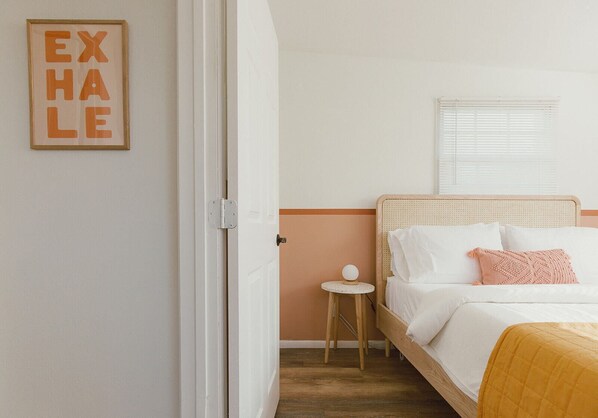 Second bedroom with a cane headboard + queen size bed that anchors the room.