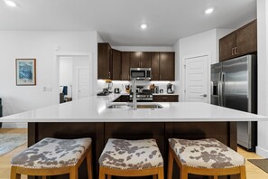 Full kitchen with stainless steel appliances, and breakfast bar seating for 3.