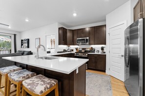 Full kitchen with stainless steel appliances, and breakfast bar seating for 3.