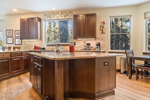 The fully equipped kitchen is a beautiful space with granite countertops, stainless steel appliances, and an over-the-sink window with tree views.