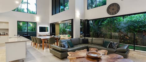 The living area is framed by soaring ceilings and oversized windows that drench the space in natural light and and bring the tropical vibes inside.