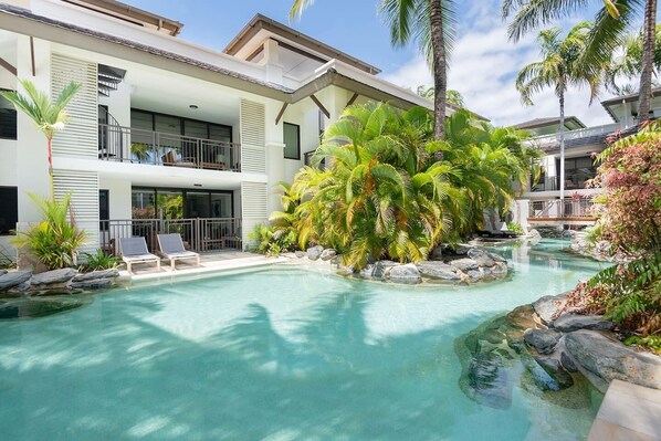 Immerse yourself in tropical vibes as you enjoy the pool, surrounded by lush greenery. Take in this serene view from the property's balcony.