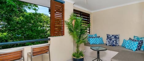 A leafy private balcony offers ample seating for guests to unwind outdoors under the gentle breeze of a ceiling fan.