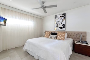 The bedroom is set with a king-sized bed fronting a wall-hung TV for easy viewing.