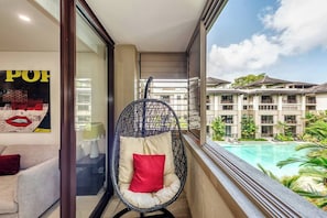 A hanging chair on the balcony is peacefully tucked away, ready for you to curl up and watch the clouds pass by over the pool.