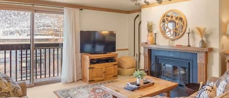 The living room is a cozy and inviting space perfect for relaxing as you warm up by the wood-burning fireplace or watch a show on the 55-inch flat-screen TV.