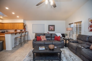 Main living room with fireplace, 65 in flat screen, couches include recliners