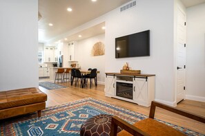 The living room boasts abundant natural light, a welcoming electric fireplace, and large screen TV.