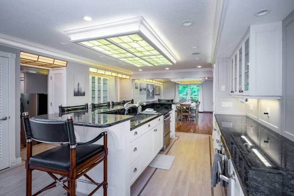 The gourmet kitchen features an island with seating for six and is equipped with stainless steel appliances, including a microwave, gas stove, and spacious refrigerator.