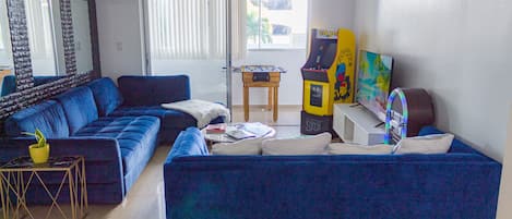 2 sofas, a smart TV, a Pac-Man arcade, and a jukebox, adding music to the room. 