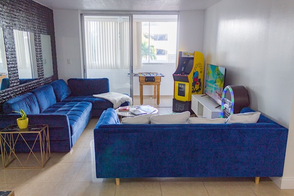2 sofas, a smart TV, a Pac-Man arcade, and a jukebox, adding music to the room.