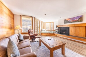 Living area with mounted flat screen TV, hardwood flooring, wood burning fireplace, queen size sleeper sofa and access to the private balcony.