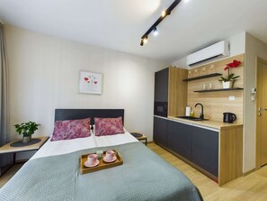 The functional combination of a bedroom area with a double bed and a kitchenette creates a practical yet cosy space.