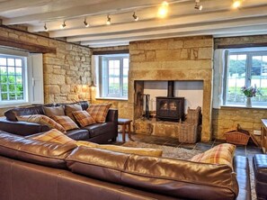 The lounge, with log burner and leather sofas, and a view of the Pele Tower