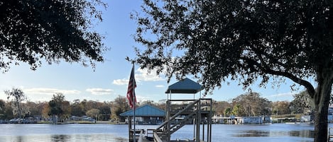 Paver walkway to dock with covered lift, upper deck, and additional boat parking