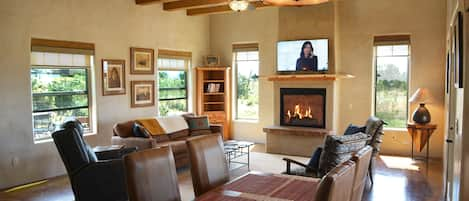 Dining area to warm inviting living room with gas fireplace and flat large flatscreen steam TV.