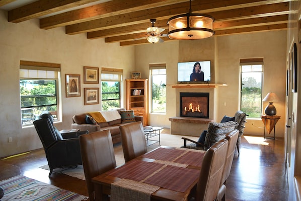 Dining area to warm inviting living room with gas fireplace and flat large flatscreen steam TV.