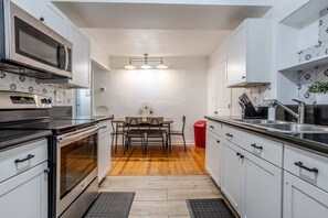 Kitchen with a 4-burner stove and oven, microwave above the stove, large double-door refrigerator, and spacious cabinets for organized storage.