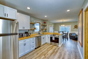 Explore another angle of our farmhouse kitchen, showcasing stainless steel appliances including a refrigerator, dishwasher, oven, toaster, microwave, coffee pot, and hot water kettle. Every detail is designed for your convenience and culinary delight.