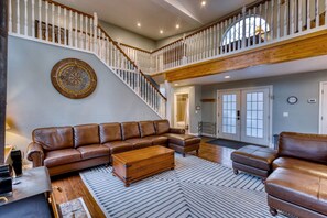 Welcome to our spacious living room! Relax on the plush leather couch in our airy living room, framed by stunning vaulted ceilings.