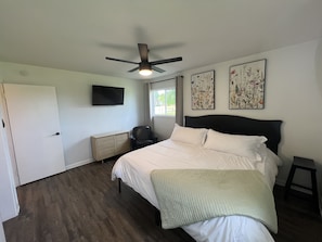 Master bedroom with king size bed and tv.