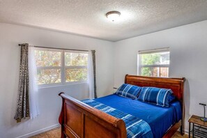 Bedroom with double bed, exterior windows, side table and lamp 