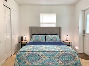 room with double bed, side tables with lamps each, window to the outside, closet door and main access door.