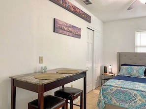 room with dining area or work laptop, bed, side table with lamp, decorations