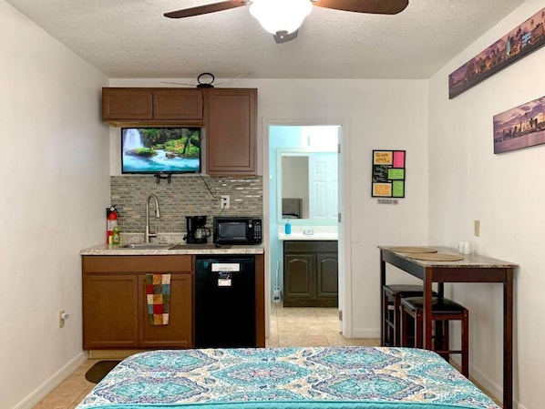 bedroom with kitchenette, microwave, fire extinguisher, tv, dining room, access to the bathroom