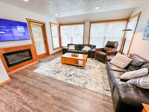 Step into the heart of comfort in our inviting living room, featuring plush leather seating, a modern electric fireplace, and abundant natural light streaming through large windows. Perfect for cozy evenings or gathering with loved ones, this space is jus