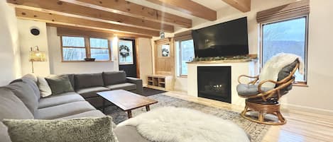 Living room with sectional couch, gas fireplace and 60” Roku TV.