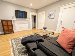 Living room with wall-mounted TV, Roku, sleeper sofa, storage, and laundry.