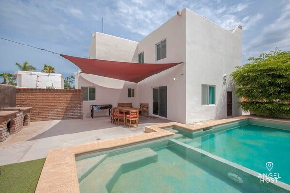 The backyard has a private enclosed pool area with shaded outdoor dining & charcoal grills