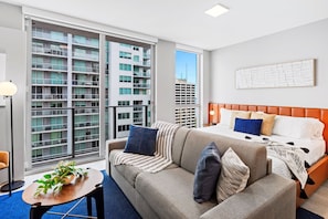 Living/sleeping area w/ king bed, 65" Smart TV - This studio apt. has large windows that will give you panoramic views of the city while resting in this cozy couch.