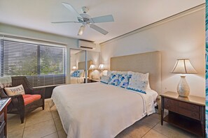 Sleep in comfort in this king-sized bed with stylish tropical decor, plush pillows, and warm ambient lighting for a restful night's sleep.
